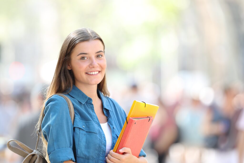Young student smiling holding books.