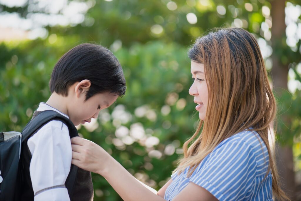Mother fixing son's backpack before school.