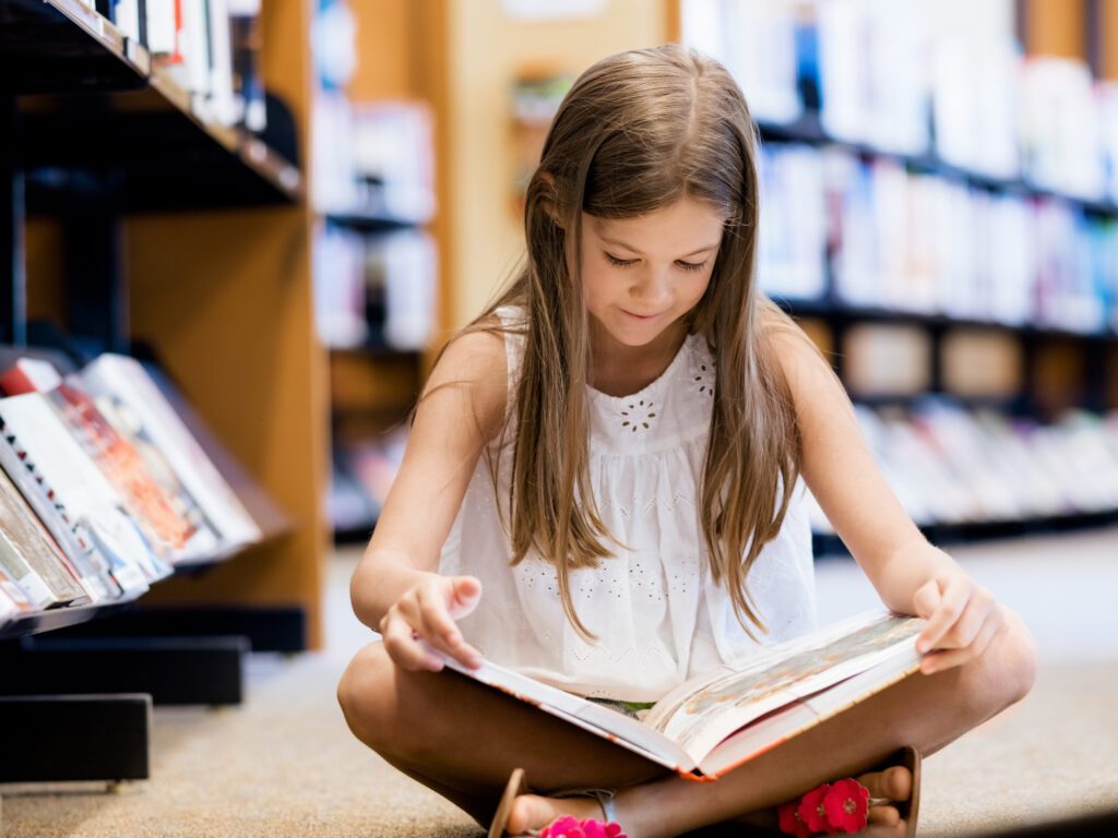 Little girl reading a book in library